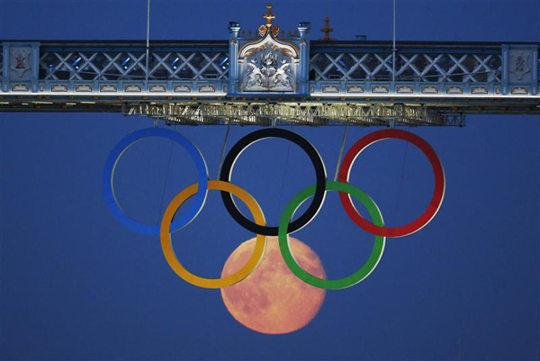 The full moon rises through the Olympic Rings hanging beneath Tower Bridge during the London 2012 Olympic Games